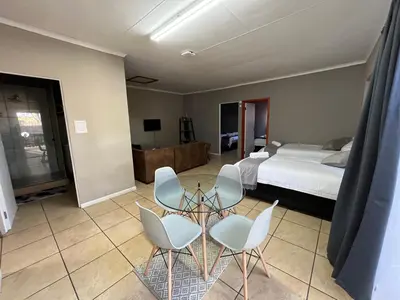 a bedroom with a bed and a table and chairs at 1 on Titania in Polokwane