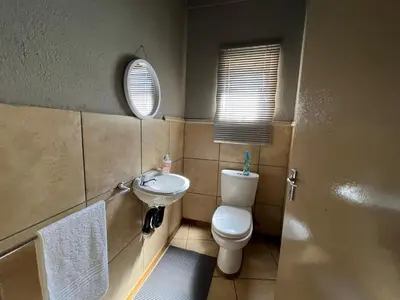 a bathroom with a toilet and a sink and a mirror at 1 on Titania in Polokwane