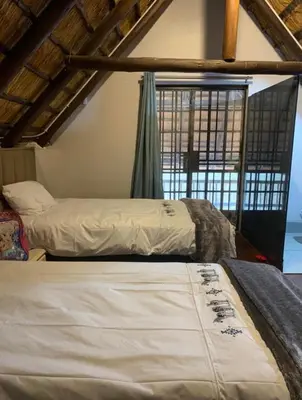 two beds in a room with a window at Kruger Nest in Marloth Park