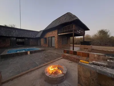 a brick building with a fire pit and a pool at Kruger Nest in Marloth Park