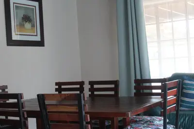 a dining room with a wooden table and chairs at Kruger Nest in Marloth Park