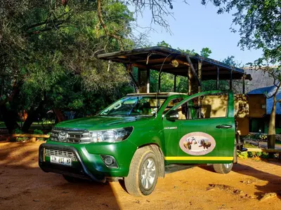 a green pick up truck parked in a field at Kubu Safari Lodge in Hoedspruit