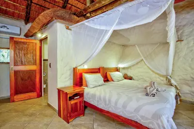 a bedroom with a canopy bed with a wooden night stand at Kubu Safari Lodge in Hoedspruit