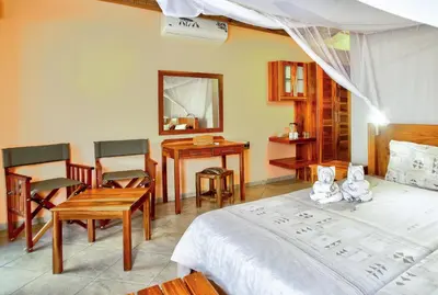 a bedroom with a bed and a table and chairs at Kubu Safari Lodge in Hoedspruit