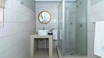 a bathroom with a sink and a shower with a mirror at Plumtree Lodge in Polokwane