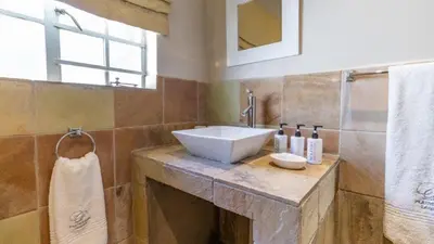 a bathroom with a white sink and a window at Plumtree Lodge in Polokwane
