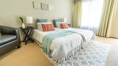 a bedroom with a large bed with pillows and a chair at Plumtree Lodge in Polokwane