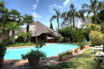 a swimming pool in a resort with palm trees at Plumtree Lodge in Polokwane