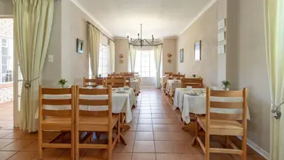 a restaurant with tables and chairs in a room at Plumtree Lodge in Polokwane
