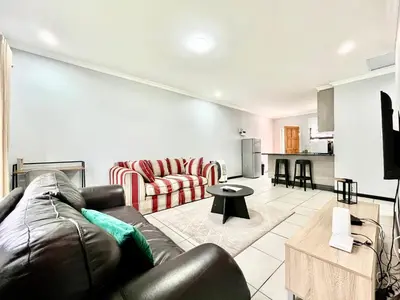 a living room with a leather couch and a kitchen at Comfort in Glen Austin, Midrand in Midrand