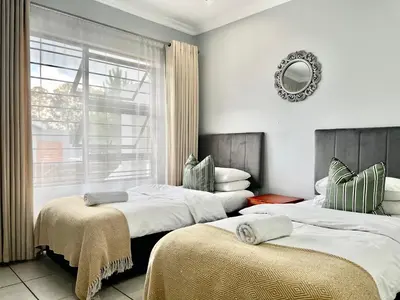 two beds in a room with a window and a mirror at Comfort in Glen Austin, Midrand in Midrand