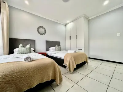 a bedroom with two beds and a mirror on the wall at Comfort in Glen Austin, Midrand in Midrand