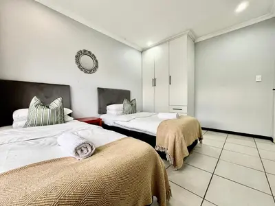 a bedroom with two beds and a mirror on the wall at Comfort in Glen Austin, Midrand in Midrand