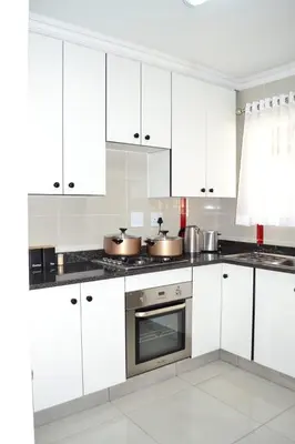 a white kitchen with white cabinets and pots and pans at Soldout Camp 2 in Pretoria