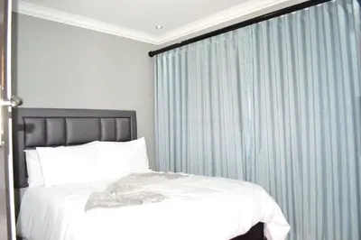 a bedroom with a bed and a blue curtain at Soldout Camp 2 in Pretoria