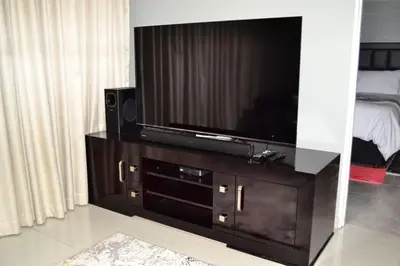 a flat screen tv sitting on top of a wooden entertainment center at Soldout Camp 2 in Pretoria