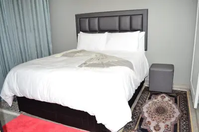 a bedroom with a white bed and a red rug at Soldout Camp 2 in Pretoria
