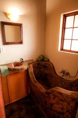 a bathroom with a large wooden tub and a sink at Bushvilla's Silonque in Phalaborwa