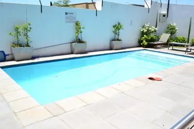 a swimming pool with blue water and potted plants at Soldout Camp 1 in Johannesburg