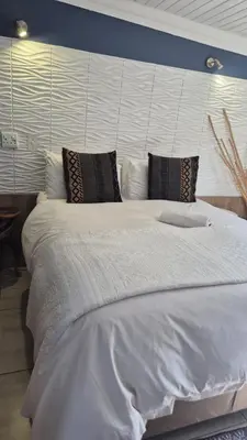 a large white bed with black pillows in a bedroom at 44 on Ennis Guest Lodge and Restaurant - in Ermelo
