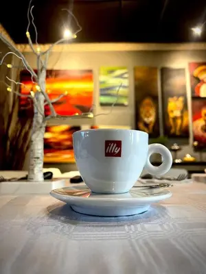 a white coffee cup sitting on a table at 44 on Ennis Guest Lodge and Restaurant - in Ermelo