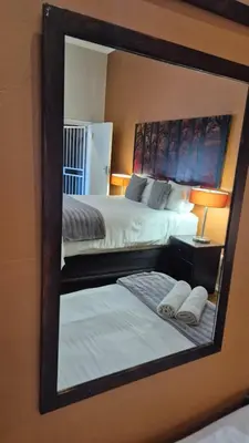 a mirror reflection of a bedroom with two beds at 44 on Ennis Guest Lodge and Restaurant - in Ermelo