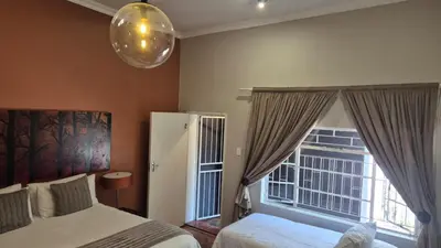 a bedroom with two beds and a large window at 44 on Ennis Guest Lodge and Restaurant - in Ermelo