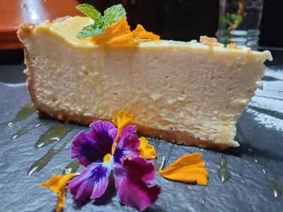 a piece of cheesecake with a purple flower on a table at 44 on Ennis Guest Lodge and Restaurant - in Ermelo