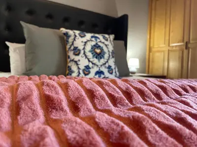 a bed with a pink blanket and a pillow on it at Betel in White River