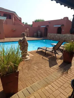 a statue standing next to a swimming pool at El Gran Chaparral Guest House in Pretoria