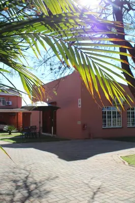 a red building with a palm tree in front of it at El Gran Chaparral Guest House in Pretoria