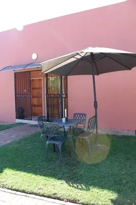 a table and chairs under an umbrella in front of a house at El Gran Chaparral Guest House in Pretoria