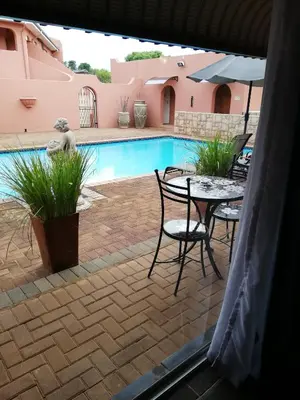 a patio with a table and chairs next to a pool at El Gran Chaparral Guest House in Pretoria