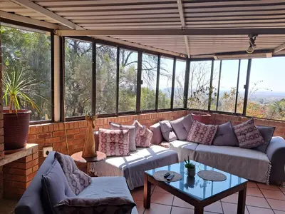 a screened in porch with couches and a table at Edelweiss Corporate Guest House in Pretoria