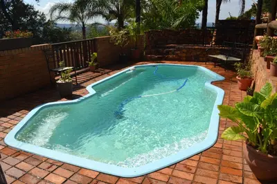 a swimming pool on a brick patio at Edelweiss Corporate Guest House in Pretoria