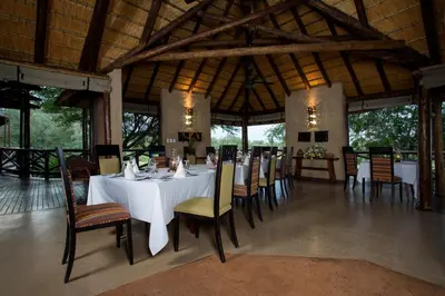 a dining room with a white table and chairs at Lukimbi Safari Lodge in Malelane
