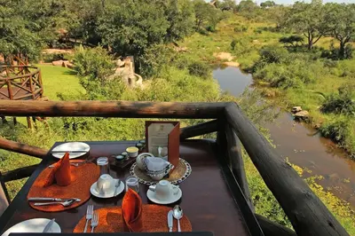 a table with food and a view of a river at Lukimbi Safari Lodge in Malelane