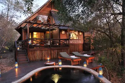 a log cabin with a hot tub on a deck at Lukimbi Safari Lodge in Malelane
