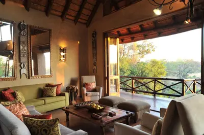 a living room filled with furniture and a large window at Lukimbi Safari Lodge in Malelane