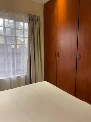 a bedroom with a bed and a dresser and a window at Thorntree Self Catering Apartment, Witbank in Witbank