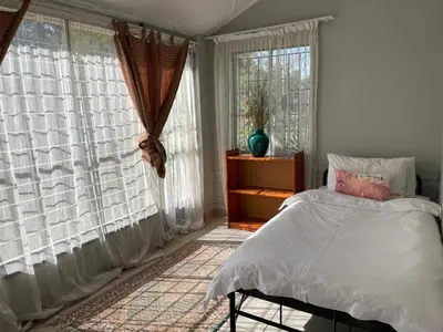 a bedroom with white curtains and a bed and a window at Smartshelter Richard in Pretoria