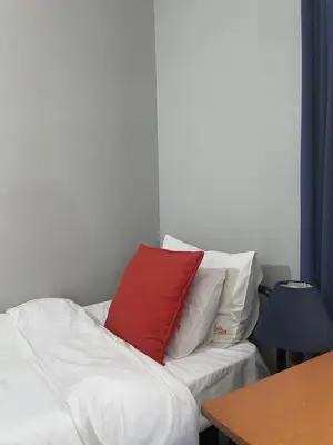 a red pillow sitting on a bed with white pillows at Smartshelter Richard in Pretoria