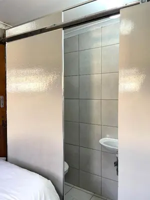 a sliding glass door to a bathroom with a sink at Smartshelter Richard in Pretoria