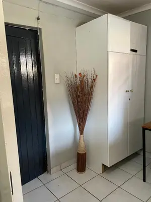 a vase with flowers in it next to a cabinet at Smartshelter Richard in Pretoria