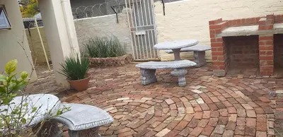 a brick patio with three benches and a fireplace at Smartshelter Richard in Pretoria
