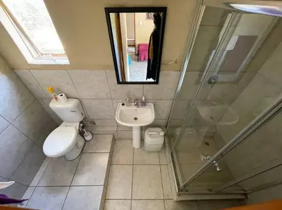 a bathroom with a toilet and a shower and a sink at 4-Bedroom Apartment in Pretoria