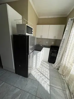 a kitchen with a black refrigerator and a microwave at 4-Bedroom Apartment in Pretoria