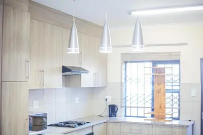 a kitchen with white cabinets and white pendant lights at Marelden security estate in Witbank