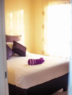 a bed with a purple towel on top of it at Marelden security estate in Witbank