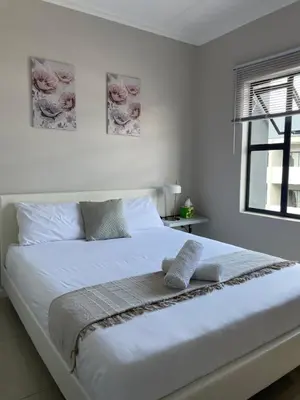 a white bed with two pillows on it in a bedroom at Classy 2 bedroom in Halfway Gardens in Midrand